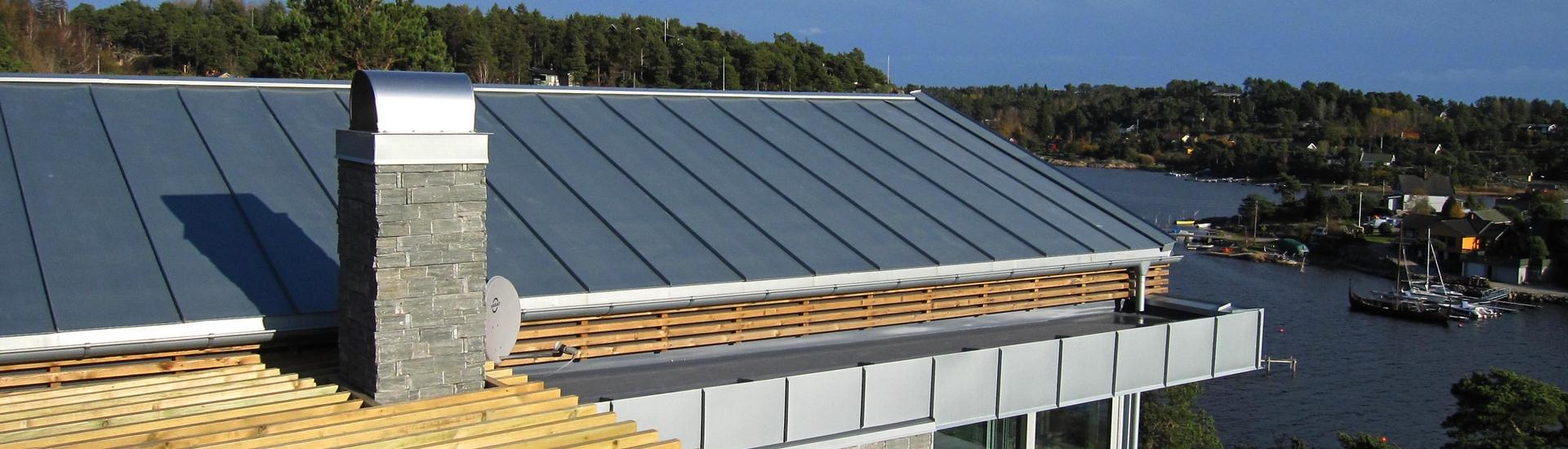 Båndtekket tak og beslått pipe på et hus ved sjøen