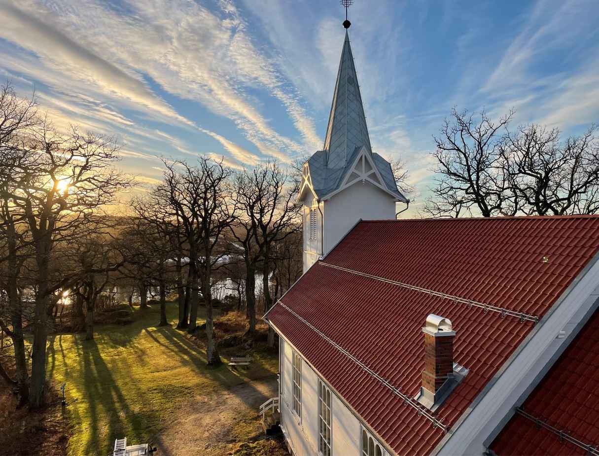 Kirketårnet på Solli kirke over et rødt teglsteinstak